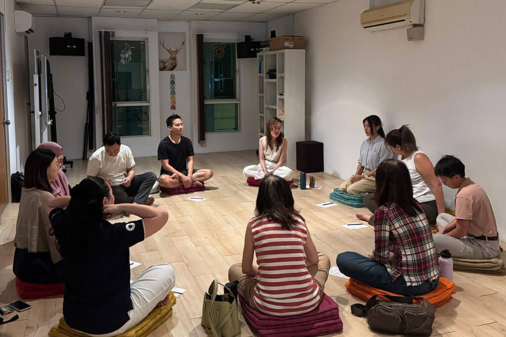 A meditation instructor guiding a small circle of students in the studio.